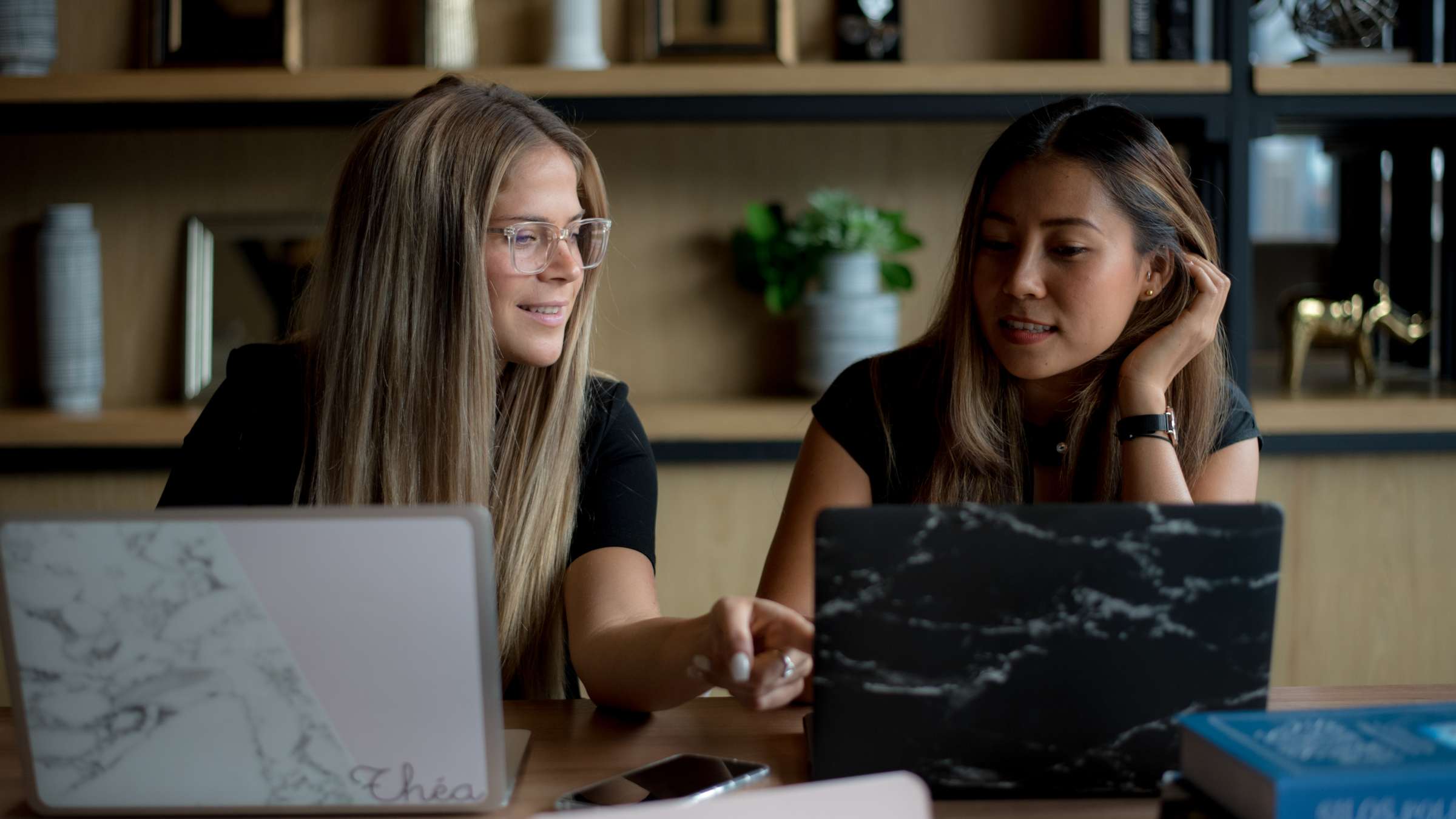 Two girls discussing in front of their laptop screens